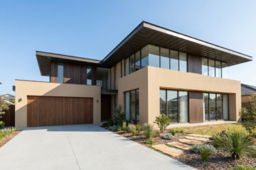 Two-storey modern Australian home exterior with timber accents and large windows under a blue sky.